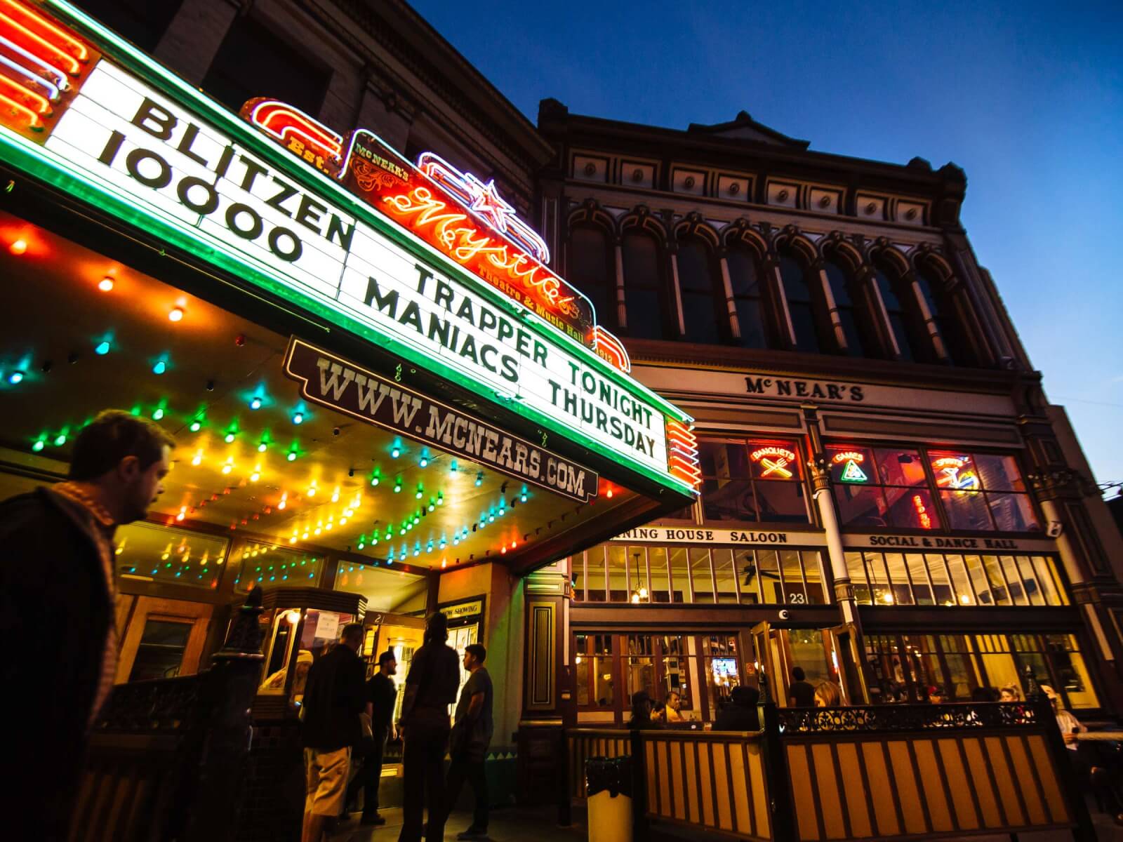 Mystic marquee with bands listed, people in front, historic theater.