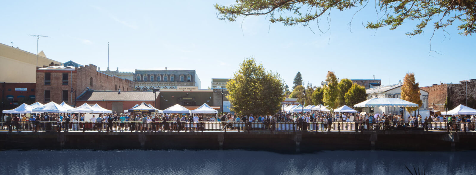 Shopping 5 Festival tents and crowds along a waterfront with historic buildings behind.