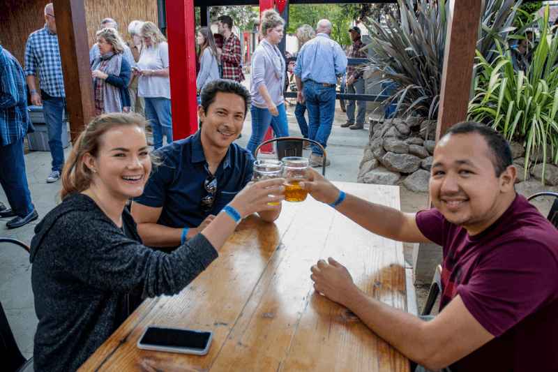 Trio clinking beers at a beer garden.