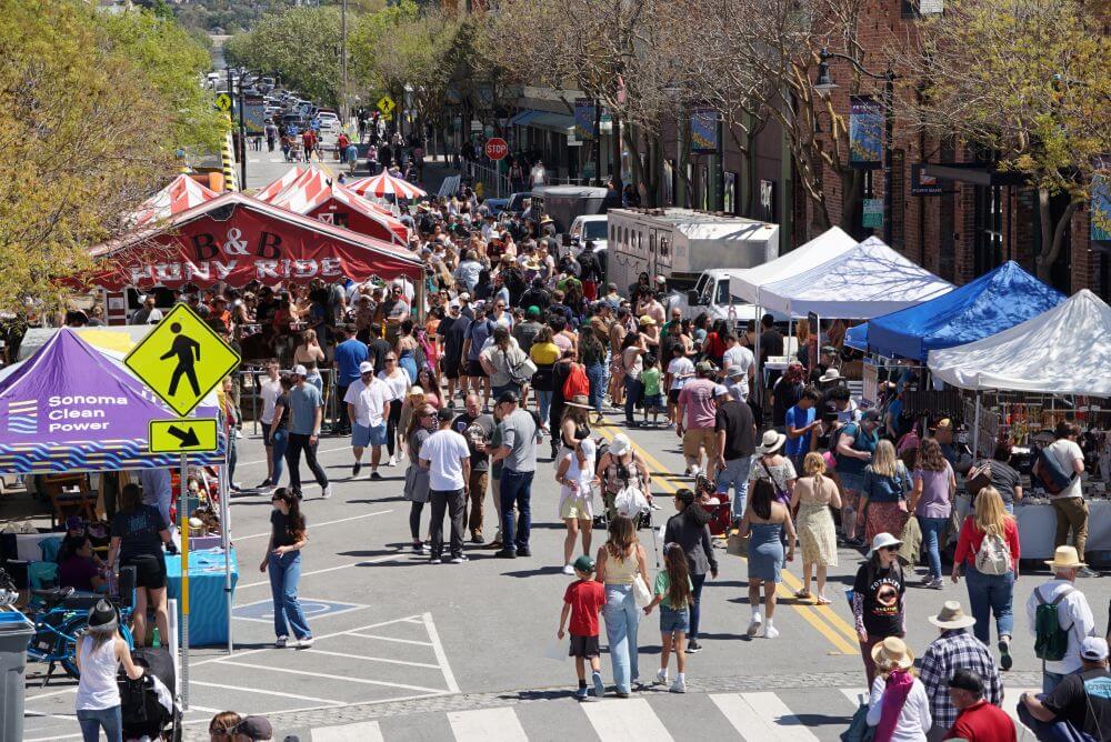 Downtown festival with many people walking down street among tents