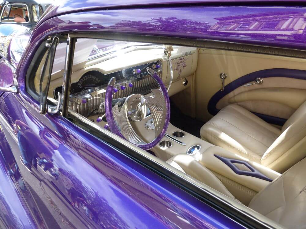 Purple classic car with purple accents on cream interior with horseshoe steering wheel