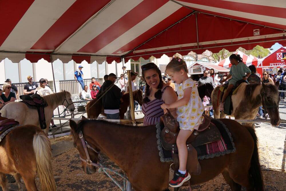 Girl on pony ride with mom by her side