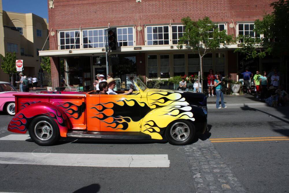 Vintage truck turned convertible with large flames emblazoned driving in car show