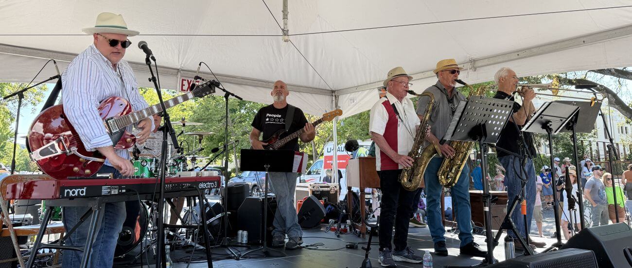 Band performing under a tent outdoors.