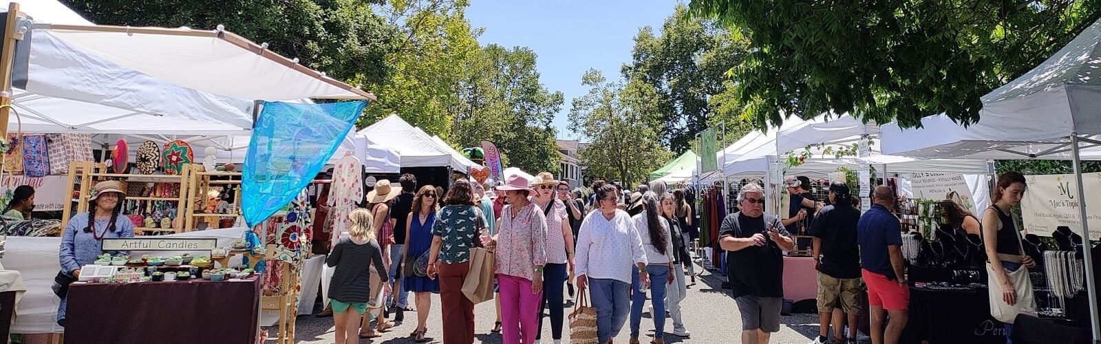 People dressed in summer clothes strolling a busy art fair