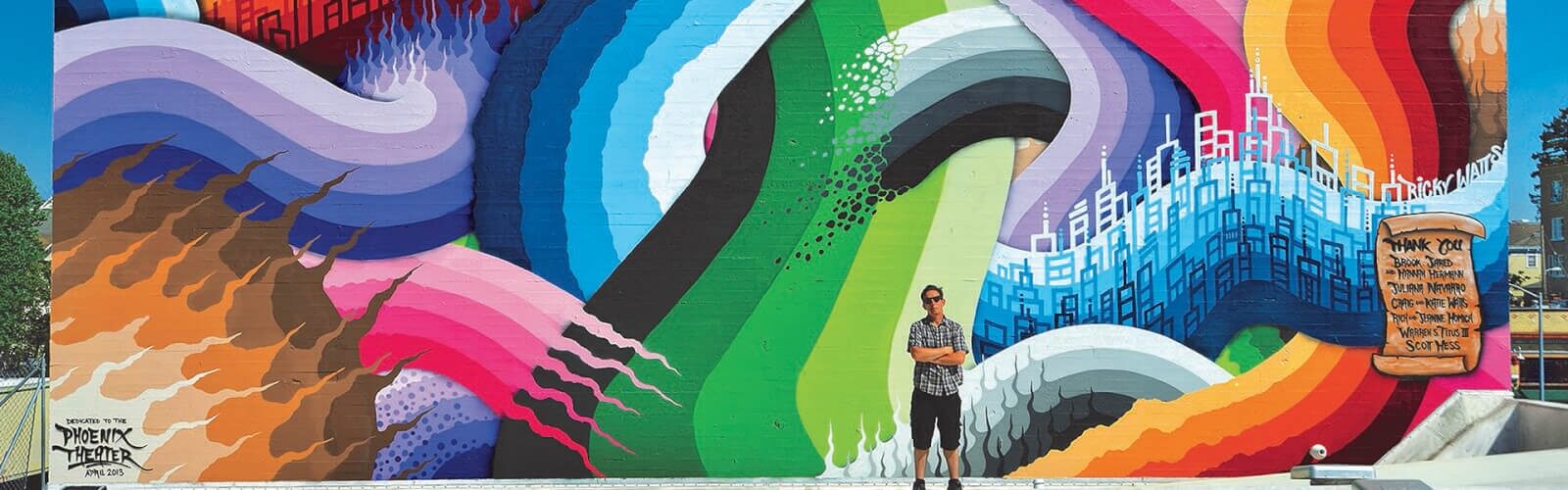 Arts & entertainment 1 Man standing with arms crossed in front of colorful mural.