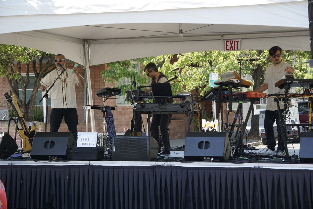 Three male band members performing on an outdoor stage