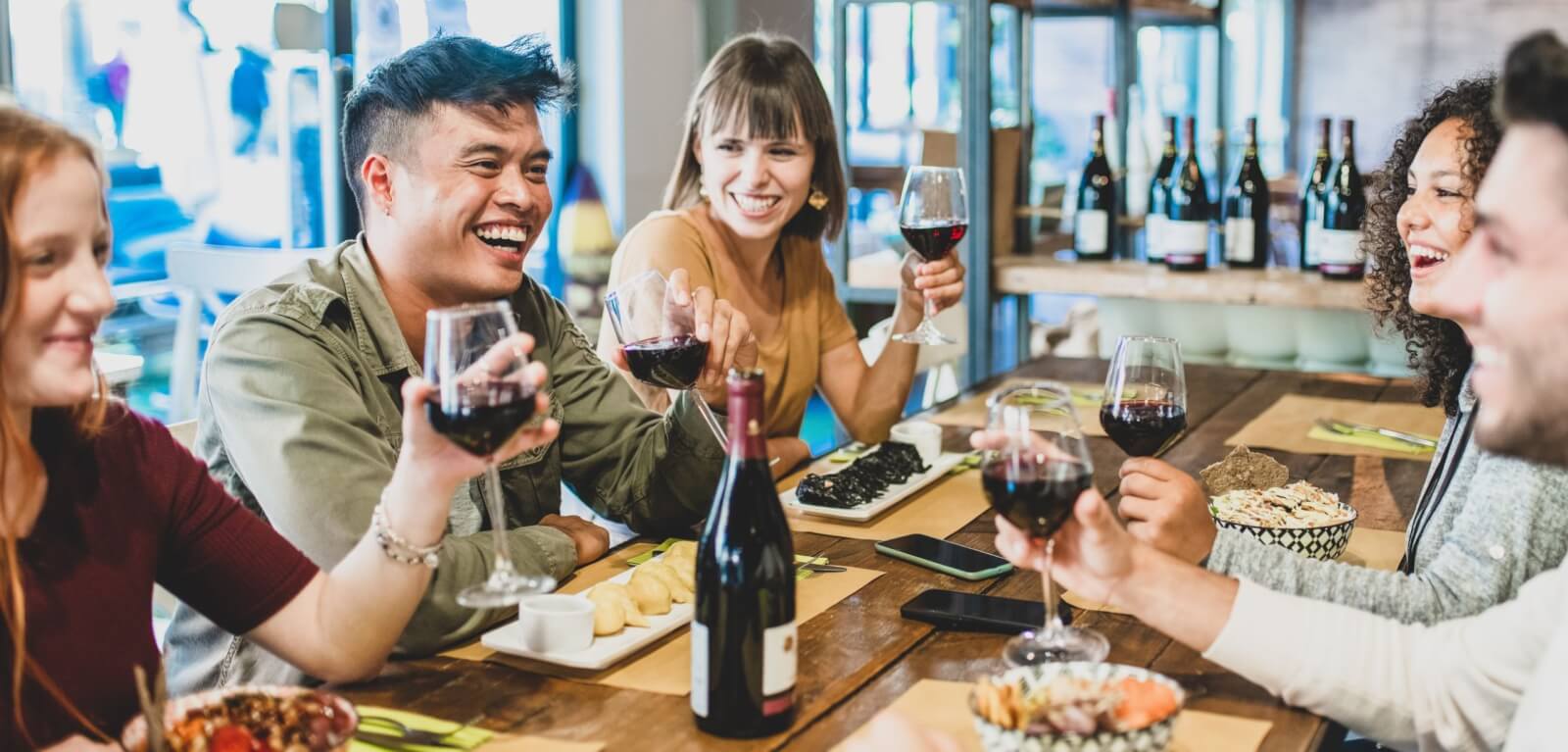 Multi-ethnic group at dinner with raised wine glasses