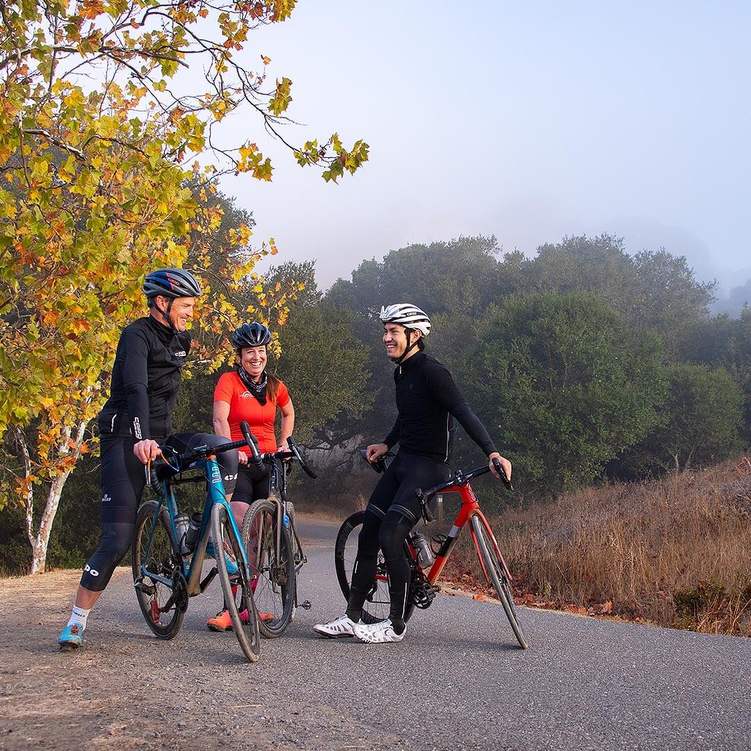 Cyclists stopping on paved trail with trees in background
