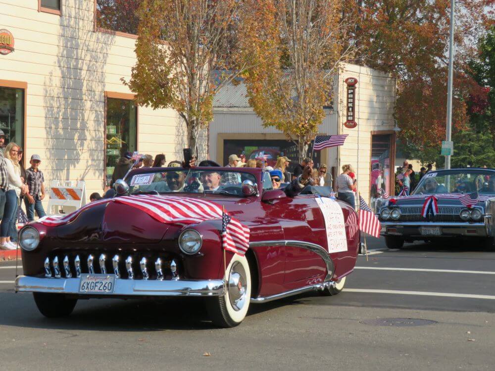 Petaluma veterans day parade & flyover 7 Vintage red car driving in parade draped in an american flag
