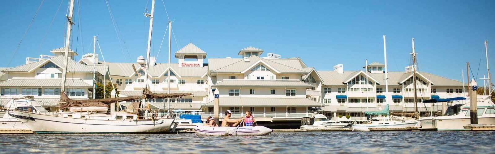 Petaluma, california 4 Family on a raft man is rowing in front of marina and sheraton hotel