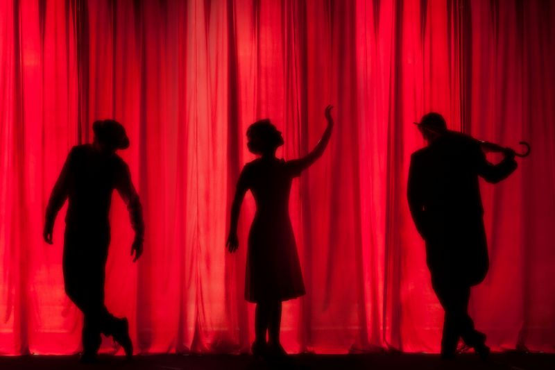 Silhouettes against a red curtain